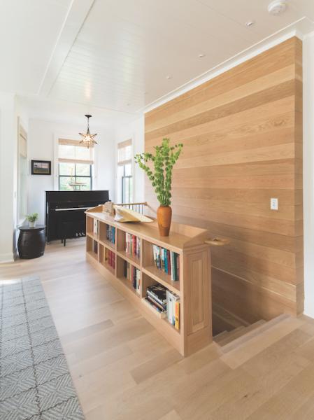 Bookcase doubles as stair railing in piano alcove in net zero house