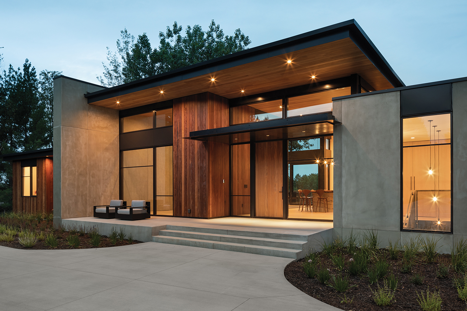 Exterior view of modern renovated home entrance with floor to ceiling windows and walnut door